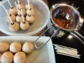 Biskuit-Cake-Pops warten auf ihre Schokoladenhülle. Geschmolzene Schokolade und Stäbchen liegen bereit.