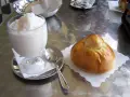 Un bicchiere di granita bianca e un soffice brioche col tuppo su un tavolo metallico.