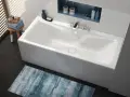 Baignoire blanche moderne, d'une largeur baignoire standard, avec robinetterie chromée et étagère murale.