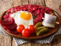 Labskaus: was ist das? Ein deftiges Gericht mit Roter Bete, Kartoffeln, Corned Beef, Spiegelei, Rollmops und Gewürzgurken.