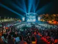 Gran concierto nocturno con multitud de público frente a un escenario iluminado con luces azules.