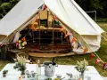 Idealne miejsce na glamping: namiot typu bell z kolorowymi chorągiewkami, stół z winem i kwiatami.