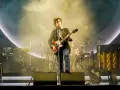 Alex Turner z Arctic Monkeys Polska na scenie, grając na gitarze w otoczeniu dymu i świateł.