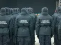Grupa funkcjonariuszy Służby Więziennej w mundurach, widok od tyłu.