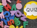 Kolorowe piankowe litery i cyfry, obok dymku z napisem "QUIZ!".
