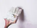 Pincel con restos de masilla para pared interior, listo para renovar.