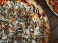 Pyszna pizza wegetariańska z pieczarkami i ciągnącym się serem, idealna na wspólny wieczór.