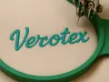 Broderie du mot "Verotex" sur un tissu beige, montrant les bases de la couture avec une machine à broder.
