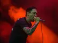 Chanteur au micro, le regard intense, comme s'il en avait marre de tout. Lumières rouges et orangées.