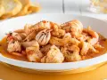 Un invitante piatto di zuppa di pesce, ricco di calamari, gamberi e pesce bianco, servito con crostini dorati.
