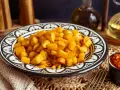 Knusprige patatas bravas in einer marokkanisch inspirierten Schale, daneben eine Schale mit scharfer Tomatensauce.