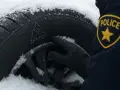 Policjant sprawdza oznaczenie 3PMSF na oponie, sugerując, czy opony wielosezonowe są dobre na zimę.