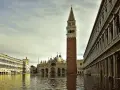 La maestosa torre di Piazza San Marco si erge sull'acqua alta, riflettendosi nel canale che lambisce i palazzi storici.