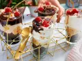 Schokoladige Dessert-Rezepte in Gläsern mit Bananen, Sahne und Kirschen. Goldene Löffel liegen bereit.