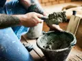 Murarz z tatuażami nabiera zaprawę murarską z plastyfikatorem na kielnię. Proporcje są kluczowe dla trwałości budowli.