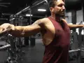 Man utför sidolyft med kabel i gymmet.