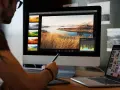 Grafika komputerowa studia: artysta obrabia zdjęcie krajobrazu na monitorze, korzystając z tabletu graficznego.