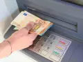 Dłoń trzyma banknoty 50 euro przy bankomacie. W Hiszpanii, jak w całej strefie euro, obowiązuje euro.