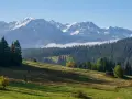 Gubałówka wysokość. Majestatyczne Tatry z ośnieżonymi szczytami górują nad zielonymi zboczami i gęstym lasem.