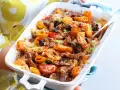 Pyszna zapiekanka gyros z makaronem, podana w białym naczyniu, z widocznymi kawałkami mięsa, oliwek i pomidorów.