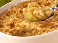 Une cuillère de crumble aux pommes, parfait pour suivre la recette Cyril Lignac. Des pommes fondantes sous une pâte croustillante.