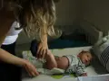 Mama zmienia pieluszkę noworodkowi. Zastanawiasz się, ile kupić pieluszek dla noworodka? Warto mieć zapas!