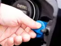 Hand schraubt blauen AdBlue-Deckel auf Diesel-Tanköffnung. AdBlue ist eine Harnstofflösung zur Abgasreinigung bei Dieselfahrzeugen.