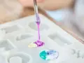 A person is learning how to make an epoxy resin mold by carefully pouring colored resin into a silicone mold.