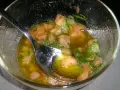 Un bol de sauce vierge recette, avec des morceaux de tomates, des herbes fraîches et une cuillère en argent.