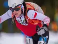 Iwona Januszyk w akcji, z determinacją na twarzy i polską flagą na rękawie, pokonuje trasę narciarską.