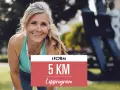 Glad kvinna redo att springa 5 km. Hennes löpprogram från iForm väntar.