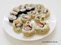 Talerz pełen pysznego california sushi, z sezamem i kolorowymi składnikami w środku.