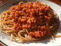 Porcja pysznego spaghetti bolognese z aromatycznym sosem mięsnym i pomidorowym, podana na talerzu z ozdobnym wzorem.