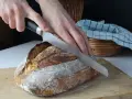 Krojenie świeżego chleba na desce. Idealna temperatura, w jakiej piec chleb, to klucz do jego chrupkości.