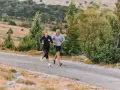 Coppia corre su strada sterrata, immersa nel verde. Il loro passo è un fondo lento, godendosi la natura.