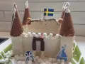En fantasifull glasstårta slott med svenska flaggan, marshmallows och en söt pingvin.