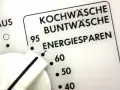 Regler einer Waschmaschine zeigt Programme wie Kochwäsche, Buntwäsche und Energiesparen. Der Wasserverbrauch hängt vom gewählten Programm ab.