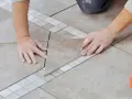 Pose d'une nouvelle dalle pour le calepinage terrasse carrelage, avec un crayon pour marquer la découpe.
