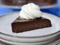 En bit fransk chokladtårta med en virvel av vispad grädde på en tallrik.