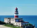 Faro blanco y rojo en la costa, un punto de referencia en la ruta de Vigo a Baiona.