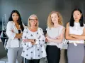 Cuatro mujeres emprendedoras, diversas en edad y etnia, posan con confianza en una oficina.
