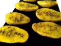 Patatas al microondas cortadas por la mitad, sazonadas con hierbas y especias, listas para cocinar.