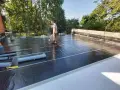 Pracownik wykonuje hydroizolację tarasu nad garażem, używając palnika do zgrzewania papy.