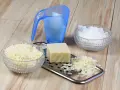 Ingrédients pour une lessive maison : savon râpé, cristaux de soude et un bloc de savon sur une râpe.