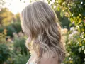 Kobieta z blond włosami w słońcu. Zastanawiasz się, jak często można nakładać toner na włosy, by utrzymać ten efekt?