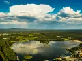 Malowniczy widok na zalew Borki otoczony lasami i zabudowaniami. Na wodzie widać łodzie, a na brzegu plażę.