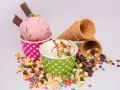 Zwei Becher mit Eiscreme, einer rosa, der andere weiß, bestreut mit bunten Streuseln und Schokostückchen. So sieht leckeres Gelato aus!