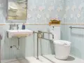Salle de bain senior : lavabo suspendu, WC avec barre d'appui rabattable et barre d'appui murale pour plus de sécurité.