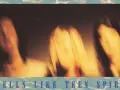 Rozmyte postacie, jakby w ruchu, na tle sugerującym okładkę albumu "Smells Like Teen Spirit" Nirvany.