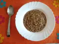Piatto di pasta e lenticchie fumante, pronto per essere gustato. Un cucchiaio d'argento attende accanto.